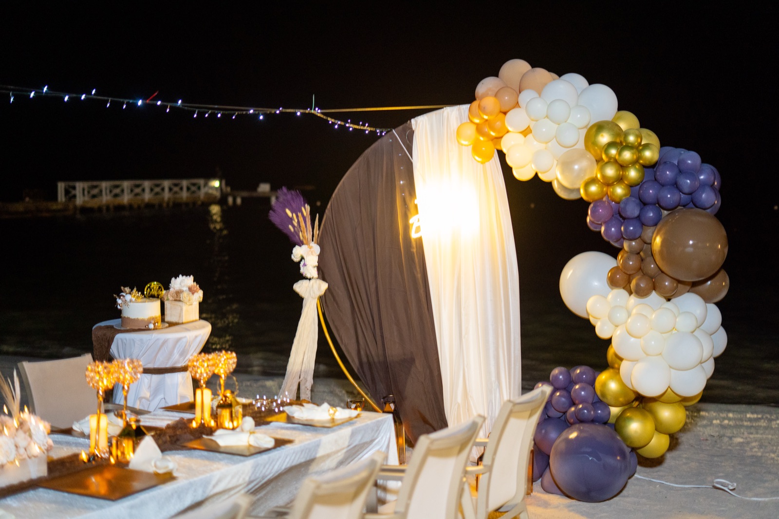 Balloon arch and draped backdrop by the sea